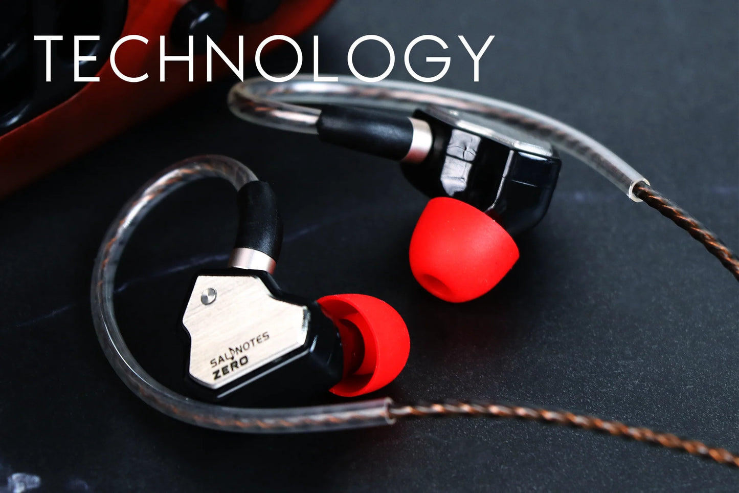 In-ear headphones with red ear tips on a dark surface, labeled 'TECHNOLOGY'.