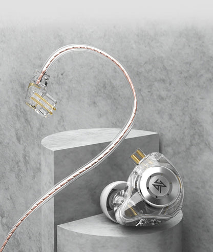 A transparent and silver KZ EDX Pro 2 earpiece with a braided cable, displayed on a gray concrete pedestal against a textured gray background.