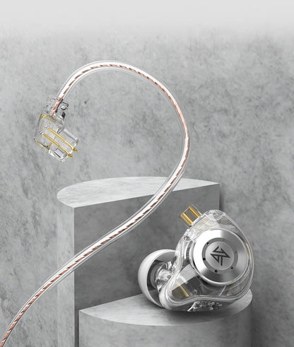 A transparent and silver KZ EDX Pro 2 earpiece with a braided cable, displayed on a gray concrete pedestal against a textured gray background.